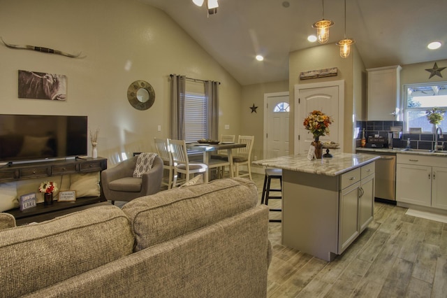 kitchen with light wood-style flooring, stainless steel dishwasher, a breakfast bar, and open floor plan