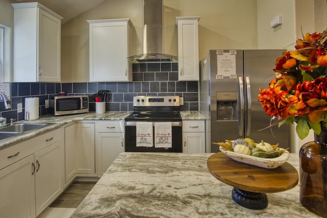 kitchen featuring backsplash, appliances with stainless steel finishes, wall chimney exhaust hood, and white cabinets