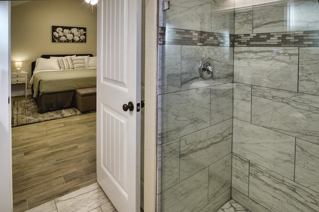 bathroom with tiled shower, wood finished floors, and ensuite bathroom