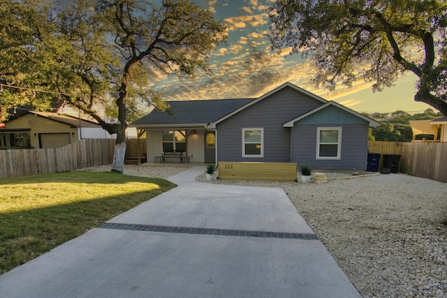 view of front facade with board and batten siding, a lawn, and fence