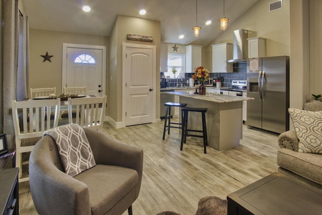 kitchen featuring visible vents, a sink, a kitchen breakfast bar, a center island, and stainless steel appliances