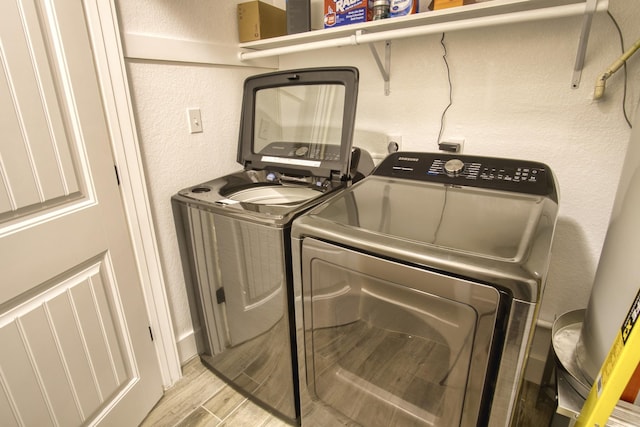 laundry area with laundry area, washing machine and dryer, a textured wall, and wood tiled floor