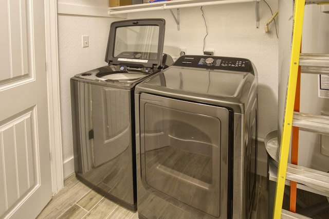 laundry area with wood tiled floor, washing machine and dryer, laundry area, and a textured wall