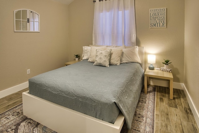 bedroom with baseboards and wood finished floors