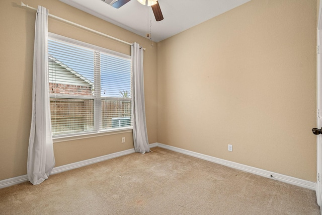 unfurnished room with a ceiling fan, baseboards, and light carpet