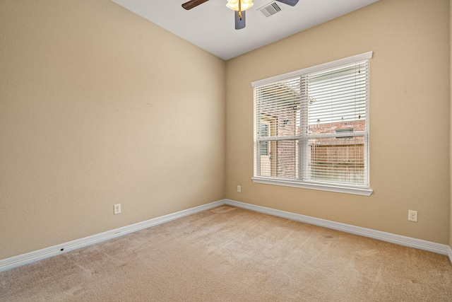 spare room featuring visible vents, light colored carpet, a ceiling fan, and baseboards