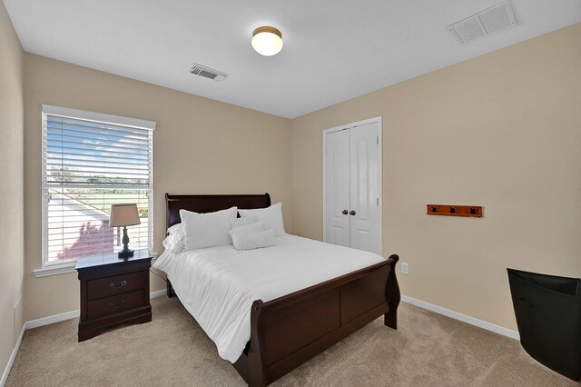 bedroom featuring light colored carpet, visible vents, a closet, and baseboards