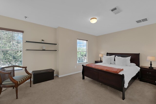 bedroom with visible vents, light colored carpet, and baseboards