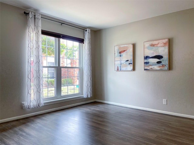 unfurnished room featuring a wealth of natural light, baseboards, and dark wood-type flooring