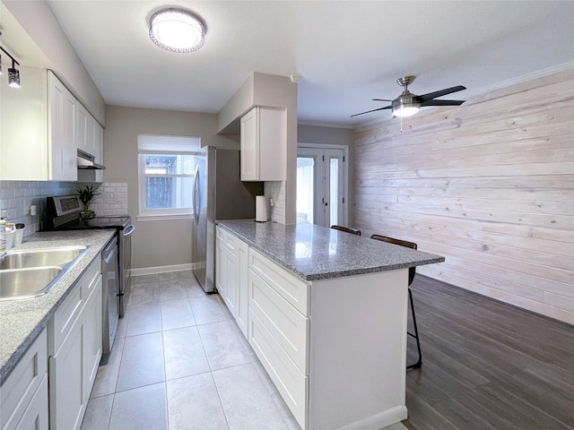 kitchen with a sink, backsplash, appliances with stainless steel finishes, a peninsula, and white cabinets