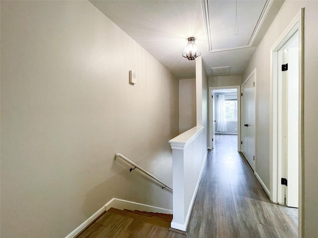 hall featuring baseboards, an upstairs landing, attic access, and wood finished floors