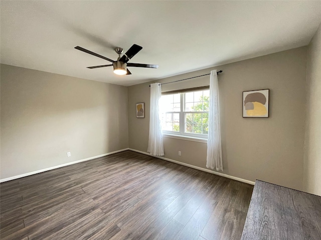 empty room with baseboards, dark wood finished floors, and a ceiling fan