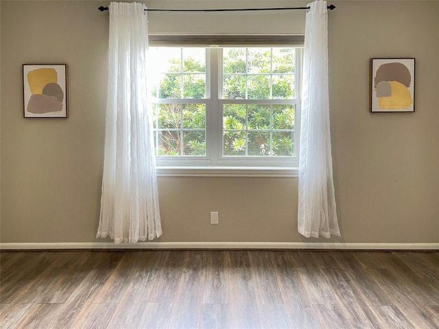 unfurnished room with baseboards, plenty of natural light, and wood finished floors