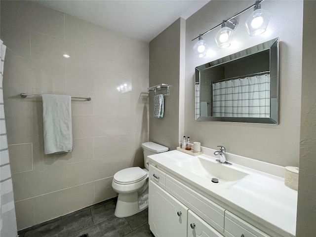 bathroom with curtained shower, tile walls, toilet, tile patterned floors, and vanity