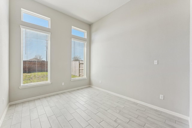 unfurnished room featuring plenty of natural light, light wood-type flooring, and baseboards