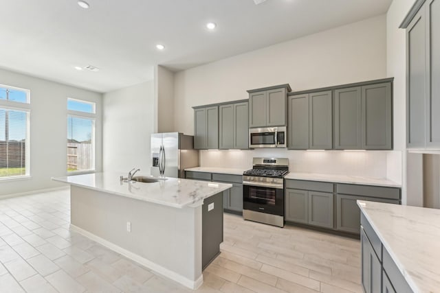 kitchen featuring a sink, tasteful backsplash, gray cabinets, and stainless steel appliances