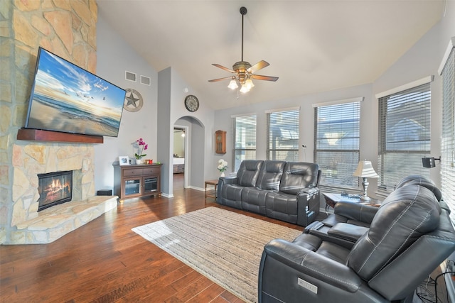 living area with visible vents, ceiling fan, a fireplace, wood finished floors, and arched walkways