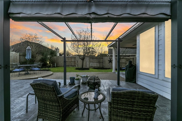 patio terrace at dusk with outdoor dining space and a fenced backyard