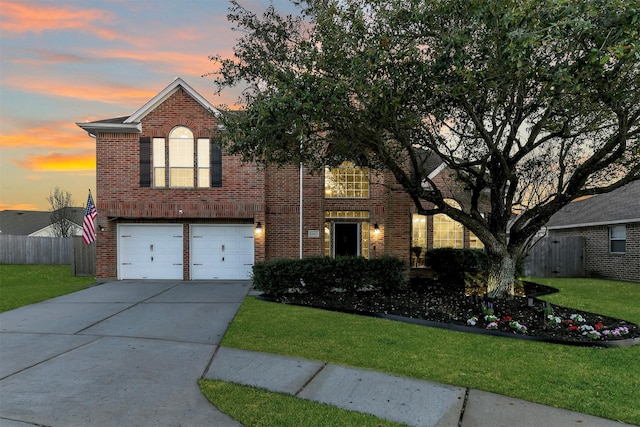 traditional-style home with brick siding, a front lawn, fence, concrete driveway, and an attached garage