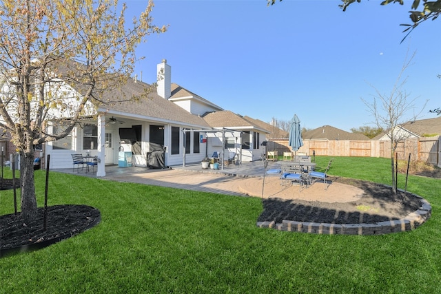 rear view of house with a ceiling fan, a patio, fence, a yard, and a chimney