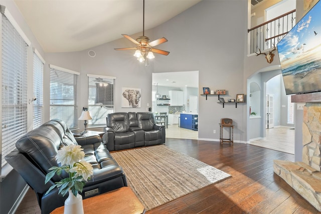 living room with dark wood-style floors, baseboards, lofted ceiling, arched walkways, and ceiling fan