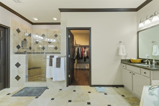 bathroom with a walk in closet, vanity, ornamental molding, and a shower stall