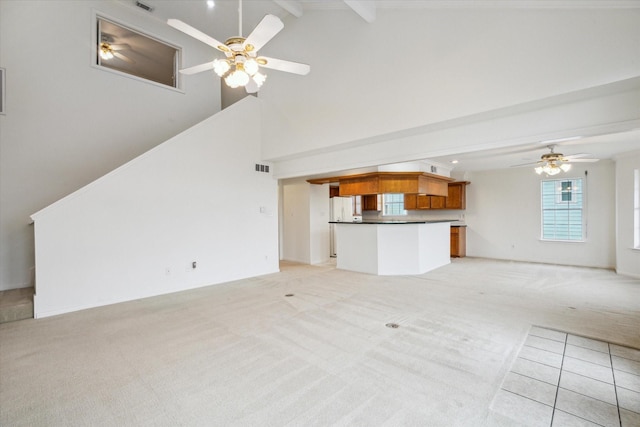 unfurnished living room featuring visible vents, ceiling fan, light colored carpet, beam ceiling, and high vaulted ceiling