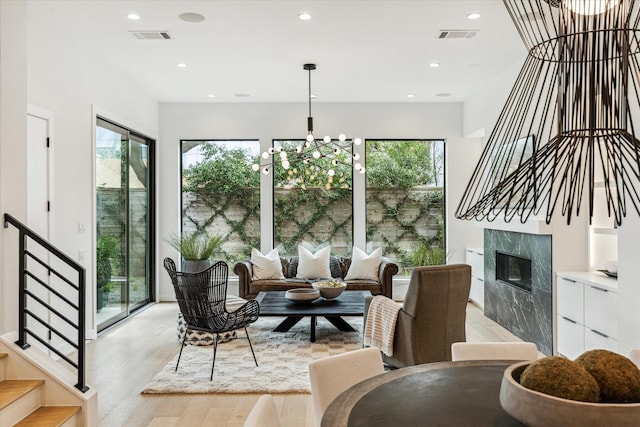 living area with visible vents, stairway, recessed lighting, light wood-style floors, and a notable chandelier