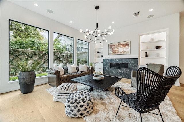 living area featuring built in features, wood finished floors, visible vents, recessed lighting, and a fireplace