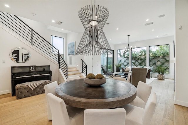 dining space featuring stairway, a notable chandelier, visible vents, and light wood-type flooring