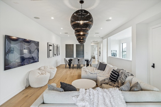 living area with a chandelier, recessed lighting, baseboards, and wood finished floors