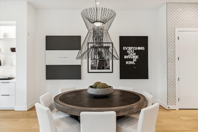 dining room with built in features, baseboards, and light wood-type flooring