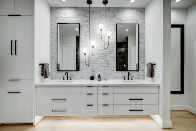 bathroom featuring a sink, decorative backsplash, wood finished floors, and double vanity