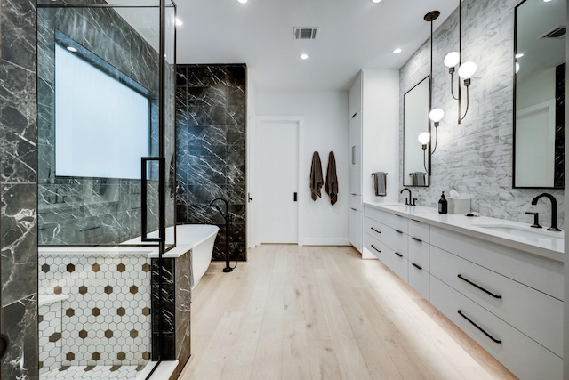 full bathroom with a tile shower, visible vents, tile walls, and a sink