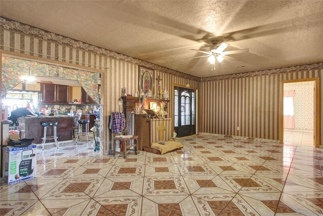 interior space featuring wallpapered walls, light tile patterned flooring, a ceiling fan, and a textured ceiling