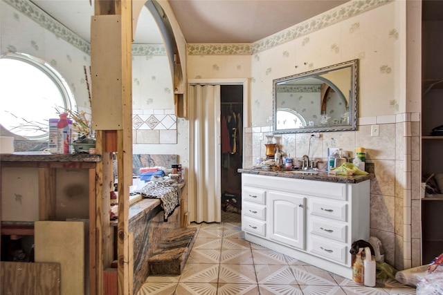 full bathroom with a wainscoted wall, wallpapered walls, and tile walls