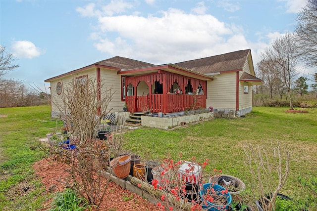 view of side of home with covered porch, a lawn, and a shingled roof