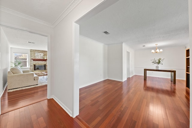 interior space with visible vents, a textured ceiling, a brick fireplace, and dark wood finished floors