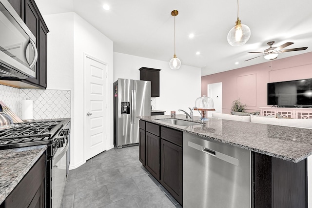 kitchen with a sink, decorative backsplash, stone counters, and stainless steel appliances