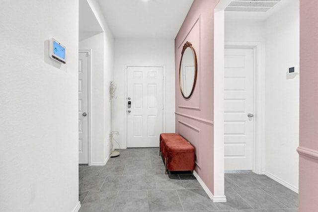 hallway with light tile patterned floors, visible vents, and baseboards