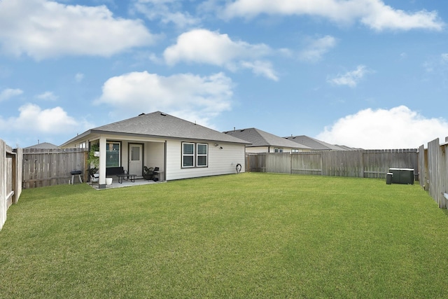 rear view of property with a yard, a patio, roof with shingles, and a fenced backyard