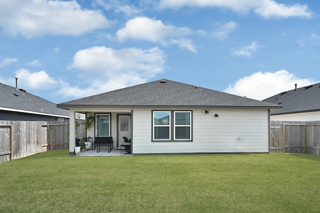 rear view of property featuring a yard, a patio area, a fenced backyard, and a shingled roof