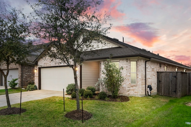 view of side of home featuring brick siding, a garage, a lawn, and driveway