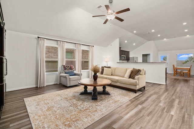 living area featuring visible vents, baseboards, vaulted ceiling, recessed lighting, and wood finished floors