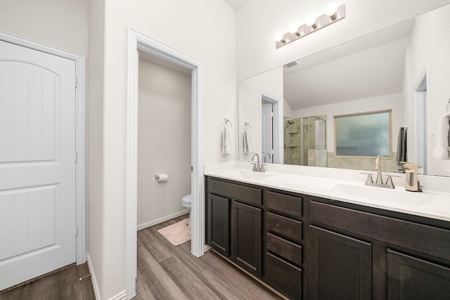 bathroom with a sink, toilet, wood finished floors, and a shower stall