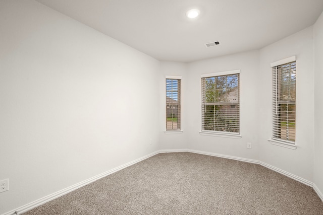 carpeted spare room featuring visible vents and baseboards