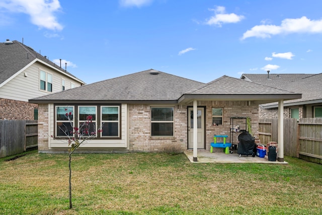 back of property with a yard, a patio area, a fenced backyard, and roof with shingles