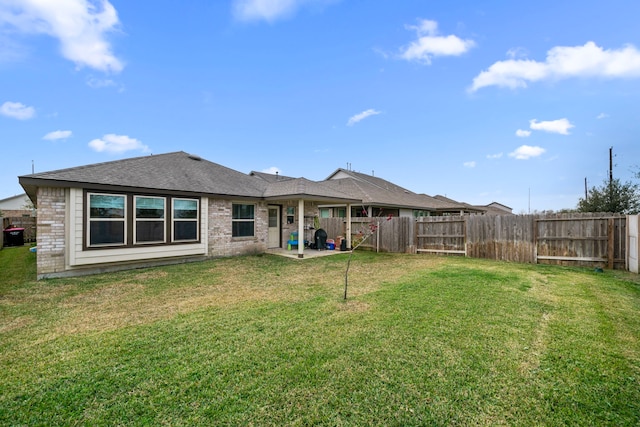 back of house with brick siding, a fenced backyard, and a lawn