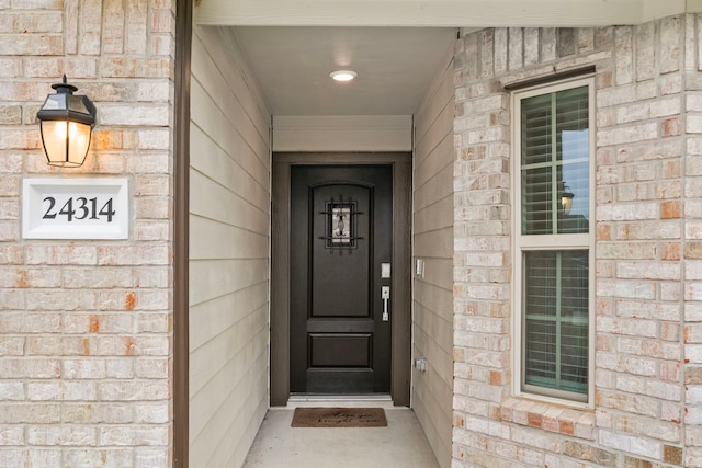 doorway to property featuring brick siding