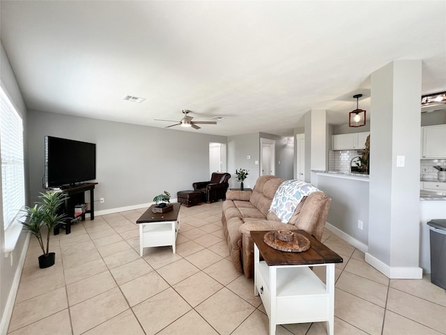 living area featuring light tile patterned floors, a ceiling fan, visible vents, and baseboards